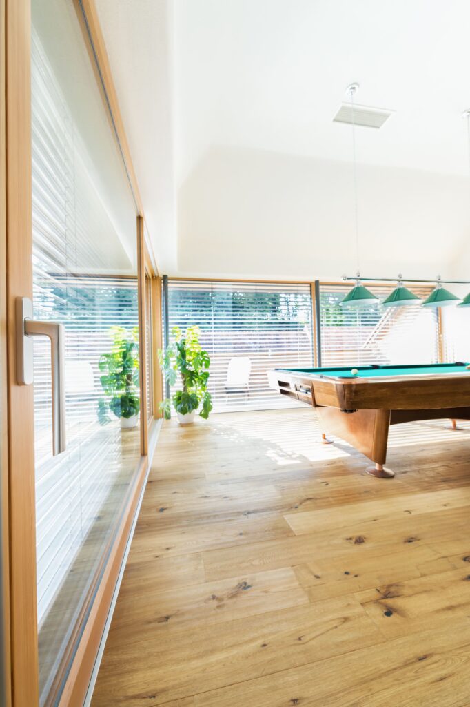 komplett verglaster Raum mit Billardtisch und großer Hebeschiebetür mit Holzrahmen