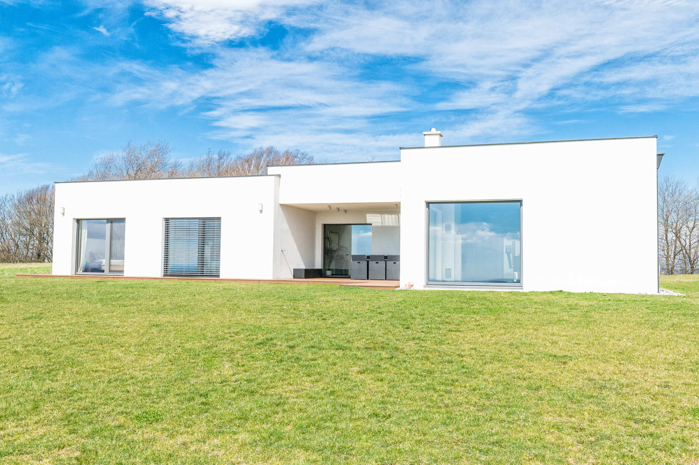 weißes Haus mit grauen Fenster und Balkontüren